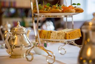 A beautifully set table for high tea featuring an assortment of pastries and desserts in a warm atmosphere | MSC Cruises