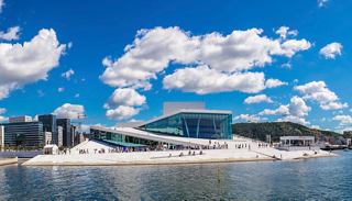 A stunning view of the Oslo Opera House with a clear blue sky and vibrant clouds above | MSC Cruises