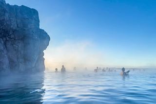 Relaxing visitors enjoy the warm waters of the Sky Lagoon surrounded by stunning Icelandic scenery | MSC Cruises
