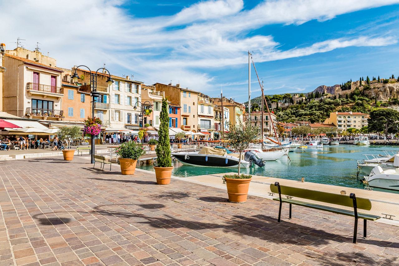 Une marina vibrante à Cassis, France, avec des bâtiments pittoresques et des bateaux sous un ciel bleu | MSC Croisières