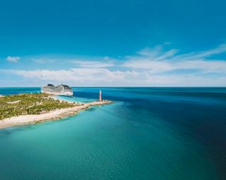 Aerial view of a serene beach and lighthouse in the Caribbean, highlighting MSC World America’s stunning destination | MSC Cruises