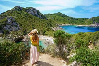 A woman enjoys a panoramic view of the sea and hills at Porto Timoni in Corfu, Greece, under a bright sky | MSC Cruises