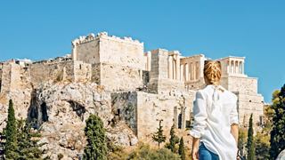 A woman gazes at the majestic Acropolis, embracing the rich history of Athens under a clear blue sky | MSC Cruises