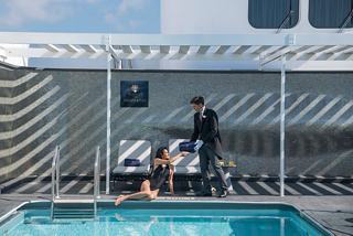 Un mayordomo sirve una bebida refrescante a un huésped junto a la piscina en la terraza del sol del MSC Yacht Club | MSC Cruceros