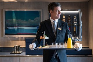 A butler serves drinks on a tray in the luxurious MSC Yacht Club, showcasing attentive service and elegance | MSC Cruises