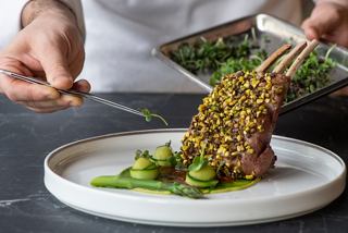 A chef elegantly plating a gourmet meat dish with courgette and asparagus using pincers | MSC Cruises