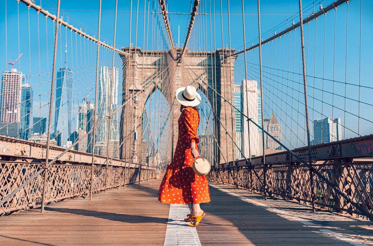 Eine Frau läuft selbstbewusst über die Brooklyn Bridge, umgeben von der ikonischen Skyline von New York City | MSC Cruises