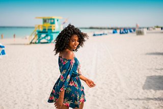 A woman wearing a floral dress walks on the beach | MSC Cruises