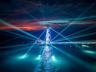 Una vista notturna mozzafiato del faro di Ocean Cay illuminato da uno spettacolo luminoso vibrante sopra il mare dei Caraibi | MSC Crociere