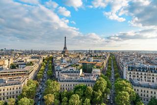A panoramic aerial view of Paris showcasing the Champs-Élysées and the Eiffel Tower under a bright sky | MSC Cruises