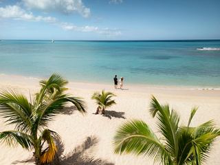 Une scène de plage sereine à Antigua avec un couple profitant de la mer et du ciel sous les palmiers | MSC Croisières