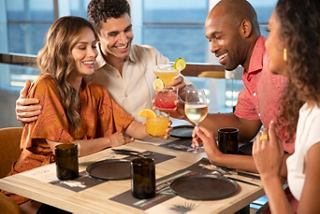 A joyful group of friends clinking cocktails together at a restaurant on MSC Seashore, celebrating life at sea | MSC Cruises