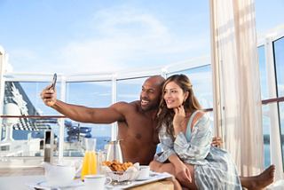 A couple enjoys a sunny moment together while taking a selfie on the MSC Yacht Club Sundeck | MSC Cruises