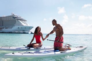 A couple enjoys stand-up paddleboarding in crystal-clear waters near the MSC Seashore in Ocean Cay | MSC Cruises