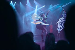 A captivating theatre performance featuring a performer in a butterfly costume illuminated by vibrant stage lights | MSC Cruises