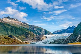 Le majestueux glacier Mendenhall reflété dans un lac serein entouré de montagnes et d'un ciel bleu clair | MSC Croisières