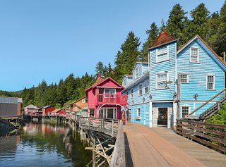 Edificios encantadores bordean el paseo marítimo a lo largo de un tranquilo arroyo en Ketchikan, Alaska, invitando a la exploración y la aventura | MSC Cruceros