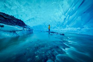 Cueva de hielo en Alaska con un hombre rodeado de hielo azul | MSC Cruceros