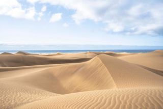 Serene sand dunes meet the tranquil sea under a bright sky, inviting exploration in Gran Canaria | MSC Cruises