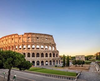 The Colosseum in Rome, surrounded by greenery and a clear blue sky | MSC Cruises