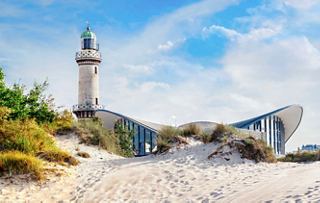 Una vista escénica del faro en Warnemünde con el edificio Teepott junto al mar | MSC Cruceros