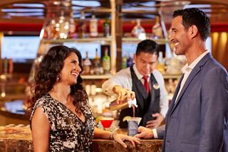 A couple enjoys a warm interaction with a crew member at the casino bar, celebrating life's moments together | MSC Cruises
