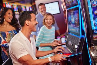 A lively casino scene with a couple and friends enjoying slot machines together | MSC Cruises