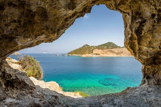 Sunny view through a rocky cave to the Greek blue sea, Patmos | MSC Cruises