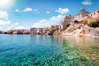 Una vista escénica de Syros con aguas claras, hermosa arquitectura y un cielo brillante sobre la costa | MSC Cruceros
