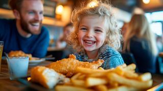 Ein kleines Mädchen genießt Fisch und Chips beim Abendessen mit ihrem Vater | MSC Cruises