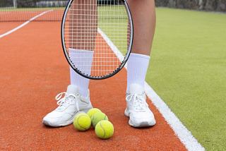 Tennis player in sportswear with a racket and balls on the court | MSC Cruises