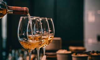 A glass of wine being poured, set in a warm and inviting bar atmosphere | MSC Cruises