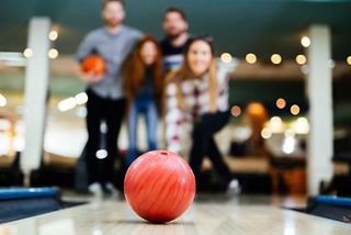 A lively group of four enjoys a fun bowling game at the sports bar on MSC Divina | MSC Cruises