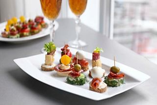 A beautifully arranged platter of gourmet canapés and appetizers alongside two glasses of refreshing drinks | MSC Cruises
