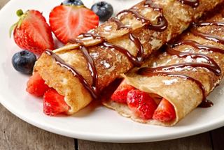 Deliciosas crepes de postre rellenas de fresas y bañadas en chocolate, acompañadas de frutas frescas | MSC Cruceros