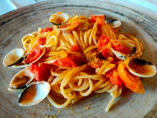 A delicious plate of pasta with clams, tomatoes, and bottarga ready to be enjoyed | MSC Cruises