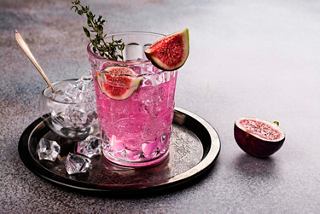 A vibrant pink cocktail garnished with fresh figs and herbs served on a tray with ice | MSC Cruises