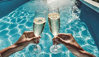 Two glasses of sparkling drinks are raised above a sparkling pool, celebrating moments of joy and togetherness | MSC Cruises