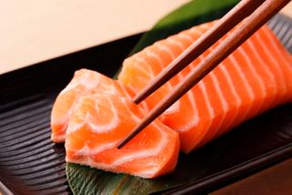 Delicious slices of salmon being picked up with chopsticks, ready to enjoy at the Asian Market Kitchen | MSC Cruises