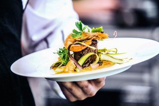 Un camarero sirve un plato bellamente presentado con camarones en el restaurante Ipanema del MSC Seaside | MSC Cruceros