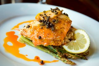A beautifully plated salmon dish garnished with herbs and served with a lemon slice, ready to be enjoyed at MSC Seashore | MSC Cruises