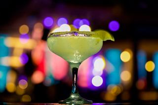 A vibrant cocktail garnished with a slice of lime, set against a colourful bar backdrop | MSC Cruises