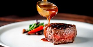 Un plato gourmet con un tierno trozo de carne rociado con una rica salsa, acompañado de verduras frescas | MSC Cruceros