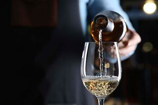 A bartender pours white wine into a glass, highlighting the elegant dining experience on board | MSC Cruises