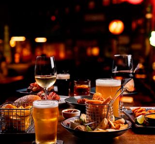 A vibrant selection of drinks and finger food on a table in a lively bar atmosphere | MSC Cruises
