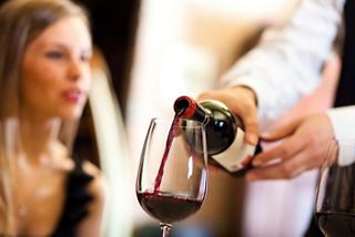 Un camarero sirve vino tinto en una copa mientras un invitado disfruta de la experiencia gastronómica en el restaurante Tribeca | MSC Cruceros