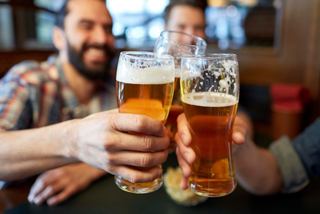 Friends toasting with glasses of beer in a lively sports bar atmosphere | MSC Cruises