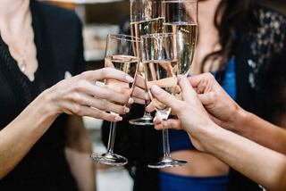 A group of friends toasting with champagne glasses, celebrating together in a vibrant bar setting | MSC Cruises