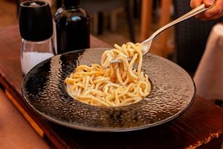 A delicious serving of pasta with cheese and pepper being lifted with a fork | MSC Cruises
