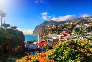 A vibrant view of Camara de Lobos village in Madeira, showcasing cliffs, mountains, and flowers against a bright sky | MSC Cruises